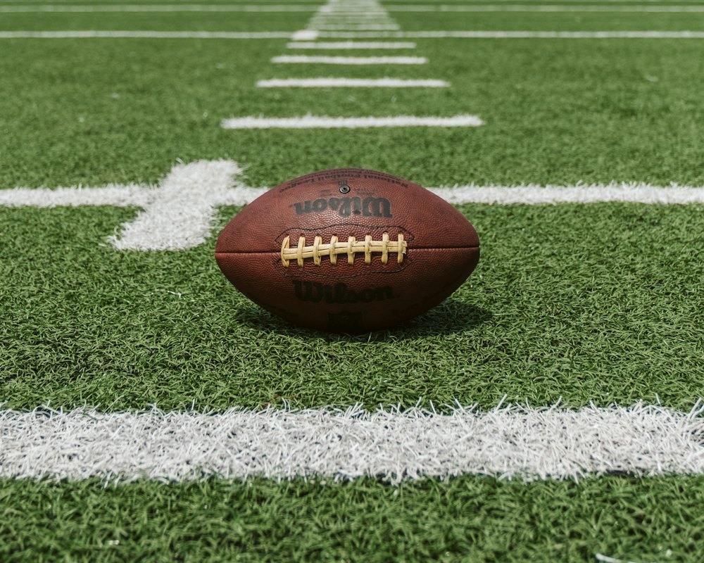 American football resting on the yard line